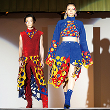 織田ファッション専門学校のファッションショーで赤と青の衣装を着てランウェイを歩く学生たち