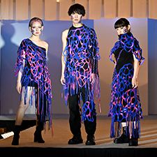 織田ファッション専門学校のファッションショーで紫の衣装を着てランウェイを歩く学生